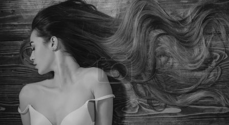 Foto de Mujer con hermoso pelo largo sobre fondo de madera. Cabello largo. Retrato de mujer de primer plano con cabello muy largo, espacio de copia.Corte de pelo de moda - Imagen libre de derechos