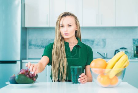 Photo for Vegetarian diet trend. Smiling young woman drinking green smoothie in kitchen. Green juice. Vegan meal diet at home. Fitness diet nutrition. Natural antioxidant. Weight loss - Royalty Free Image