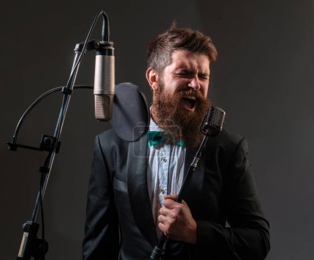 Photo for Portrait of excited man in a recording studio. Expressive bearded man in suit with microphone. Karaoke signer, musical vocalist - Royalty Free Image