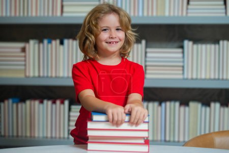 Photo for School kid pupil studying in school library. Child reading book in library on bookshelf background - Royalty Free Image