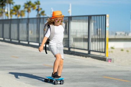 Téléchargez les photos : Petit garçon à skateboard sur la route. Un gamin qui pratique le skateboard. Les enfants apprennent à faire du skateboard dans un parc lors d'une journée ensoleillée d'été. Patinage enfant sur skateboard - en image libre de droit