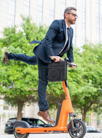 Photo for Scooter allows business man in suit to be efficient and punctual. Electric scooter provides a quick and easy for business man. Electric scooter helps funny business man make up for lost time. Fast - Royalty Free Image