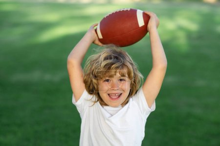 Photo for American style football. Kid boy having fun and playing american football on green grass park - Royalty Free Image