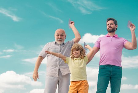 Photo for Active family leisure with kids. Boy son with father and grandfather with a toy airplane plays on summer sky background. Journey travel trip concept - Royalty Free Image