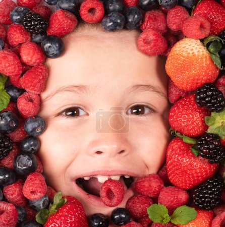 Téléchargez les photos : Vitamines de berrie. Enfants visage avec des baies mélange de fraise, myrtille, framboise, mûre - en image libre de droit