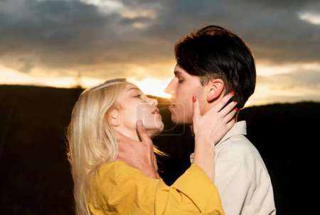 Téléchargez les photos : Jeunes amants embrassant et embrassant. Embrasse un couple aimant au coucher du soleil. Couple amoureux tendresse et affection - en image libre de droit