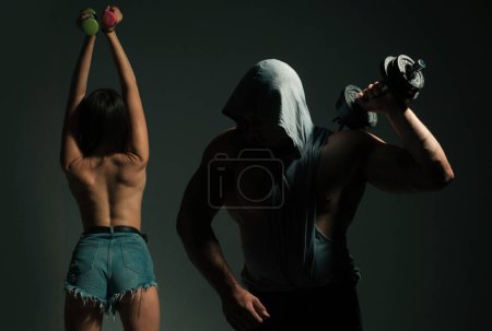 Téléchargez les photos : Couple sexy sportif avec haltères sur fond noir studio - en image libre de droit