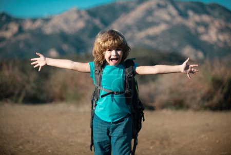 Téléchargez les photos : Enfant garçon avec sac à dos randonnée dans les montagnes pittoresques. Un jeune touriste local part en randonnée locale - en image libre de droit