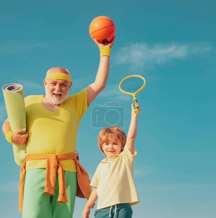 Foto de Feliz hombre mayor en forma haciendo ejercicio. Retrato de un padre y un hijo sanos trabajando sobre el fondo azul del cielo. Vida sana activa para la familia - Imagen libre de derechos