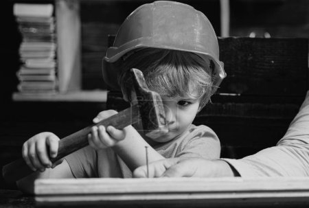 Foto de Pequeño reparador divertido con martillo. Trabajador de construcción de niños. Niño use un martillo para clavar - Imagen libre de derechos