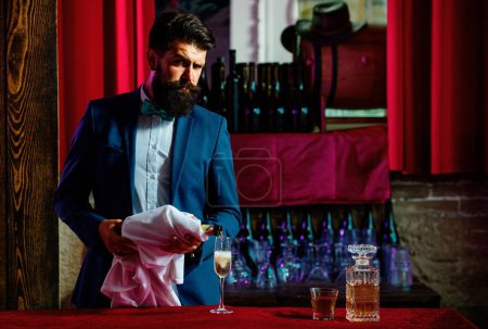 Foto de Barman sirviendo champán en una copa de champán. Barbudo hombre guapo sosteniendo vaso de wiskey - Imagen libre de derechos