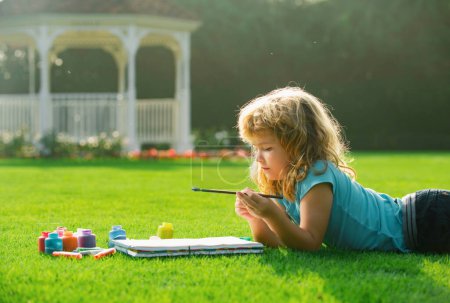 Photo for Portrait of smiling happy kid enjoying art and craft drawing in backyard or spring park. Children drawing draw with pencils outdoor - Royalty Free Image