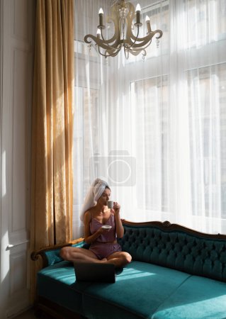 Photo for Young attractive woman drinking coffee, relaxing at home. Cozy lazy spring mornig. Beautiful girl in the mornig after sleep on bed. Relaxing female model on the bed wake up - Royalty Free Image