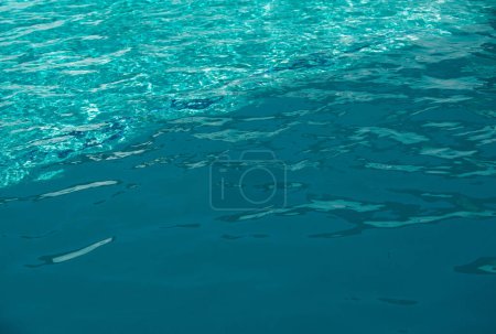 Téléchargez les photos : Bleu fond d'eau de piscine. Texture floue transparente et claire de la surface de l'eau calme. Vagues d'eau au soleil avec espace de copie - en image libre de droit