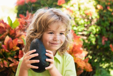 Photo for Kids summer vitamin. Little adorable child with avocado. Vitamin and healthy food for small children. Portrait of beautiful child - Royalty Free Image