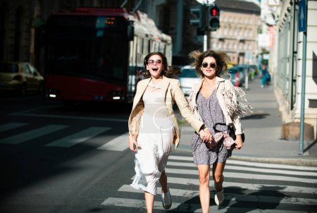 Photo for Two excited happy women walking running together on the street. Funny vacation, romantic travel - Royalty Free Image