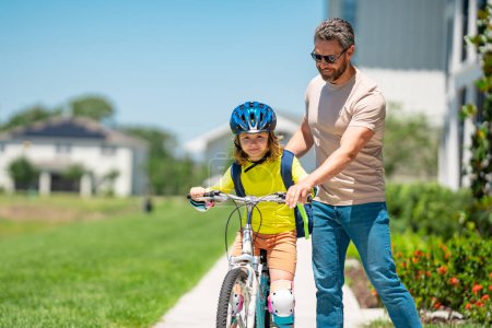 Photo for Fathers day. Boy learning to ride a bicycle with his father in park on summer day. Father teaching his son cycling on bike. Father learn little son to ride a bicycle. Father support kid. Happy Fathers - Royalty Free Image