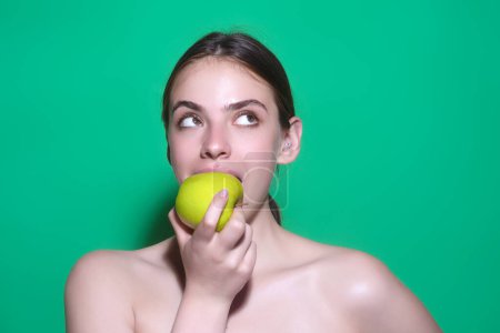 Téléchargez les photos : Des gens avec des pommes. Portrait de jeune femme mangeant des pommes isolées sur fond de studio. Des pommes saines pour des vitamines naturelles, un régime alimentaire et un mode de vie sain. Studio portrait femme manger pomme verte - en image libre de droit