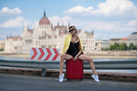 Foto de Sueños de viajar. Mujer de moda con suitcas de vacaciones. Estilo de vida. Sexy joven en viaje de negocios a pie con el equipaje en la calle - Imagen libre de derechos
