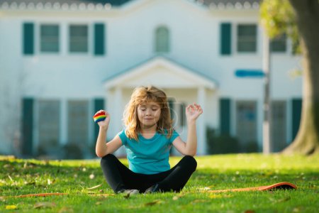 Téléchargez les photos : Enfant faisant des exercices de gymnastique, pose de lotus yoga. Enfant méditant dans la nature - en image libre de droit