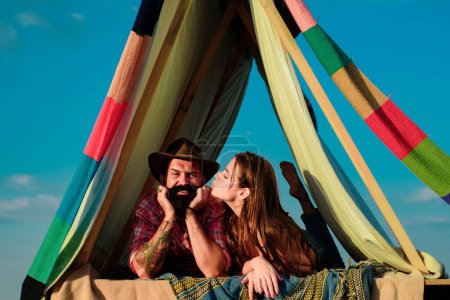 Téléchargez les photos : Randonneurs couple camping sur la nature. Amateurs romantiques en camping de vacances. Couple hipster tendre baisers dans la tente du camp - en image libre de droit