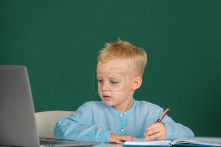 Photo for Funny face of little student of primary school study in classroom at school. Kid writing in notebook in class. Education and kids knowledge concept - Royalty Free Image