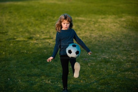 Téléchargez les photos : Boy child playing football on football field. Kid playing soccer. Concept of children sport - en image libre de droit