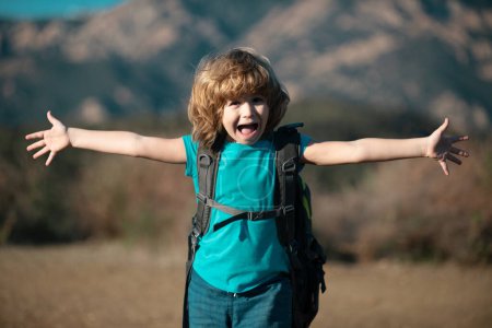 Téléchargez les photos : Petit garçon avec sac à dos randonnée dans les montagnes pittoresques. Garçon touriste local va sur une randonnée locale - en image libre de droit