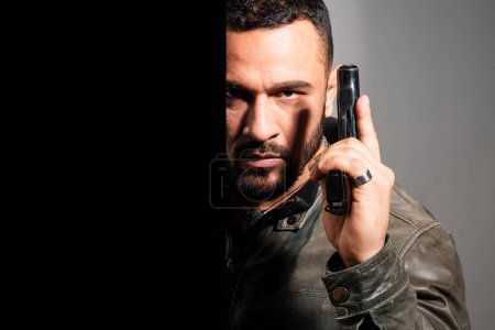 Photo for Portrait of a man holding gun. Handsome bearded man. Danger. Gunman with dark background. Serious stylish bearded man. Man with serious face and brutal style - Royalty Free Image