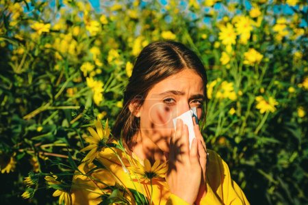 Foto de La niña sufre de alergia al polen durante la floración y utiliza servilletas. Hermosa mujer joven sexy se encuentra en el fondo de las flores. Alergia - Imagen libre de derechos