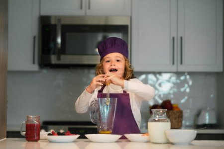 Photo for Cooking in kitchen. Chef cook child having fun preparing a cake in kitchen at home. Kid boy in chef hat and an apron cooking in the kitchen - Royalty Free Image
