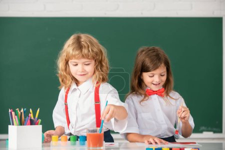 Foto de Niñas y niños dibujando con plumas para colorear. Lindos niños pintando en clase en la escuela. Lección de pintura, dibujo de arte. Educación en la primera infancia - Imagen libre de derechos