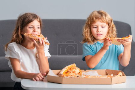 Téléchargez les photos : Les enfants mangent des pizzas. Petits enfants amis, garçon et fille mordent pizza - en image libre de droit