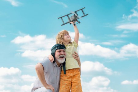 Photo for Child boy and grandfather playing with plane together on blue sky. Cute child with granddad playing outdoor. Generations ages - Royalty Free Image