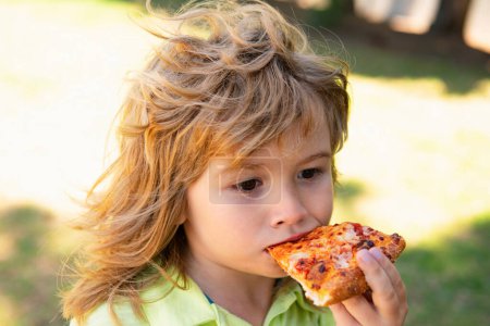 Photo for Kid boy eating pizza outdoor. Pizza the best food. Cute little child eating pizza - Royalty Free Image