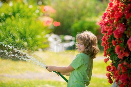 Téléchargez les photos : Adorable petit garçon arrose la plante à l'extérieur de la maison, concept d'activité d'apprentissage de la culture des plantes pour l'éducation des enfants et des enfants pour l'arbre dans la nature - en image libre de droit
