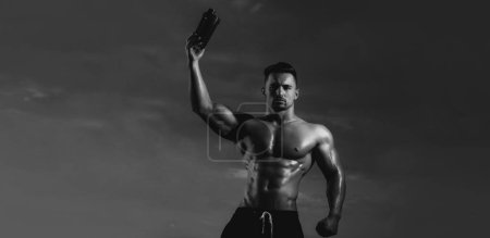 Téléchargez les photos : Humide homme musculaire avec bouteille d'eau ou de protéines. Modèles de bannière avec homme musclé, torse musculaire, six pack abs muscle - en image libre de droit
