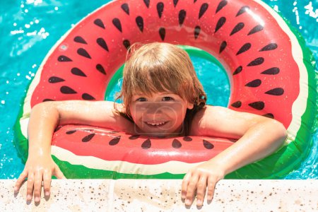 Foto de Niño nadando en el juego de piscina con anillo flotante. Sonriente lindo niño en gafas de sol nadar con anillos inflables en la piscina en el día de verano - Imagen libre de derechos