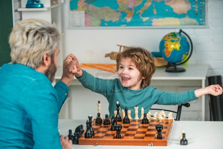 Téléchargez les photos : Jeune garçon jouant aux échecs avec son père et s'amusant. Concept d'éducation et d'apprentissage - élève et enseignant - en image libre de droit