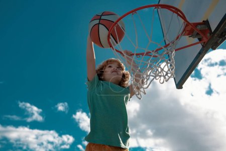 Téléchargez les photos : Enfants actifs appréciant le jeu en plein air avec basket-ball, en plein air sur l'aire de jeux - en image libre de droit