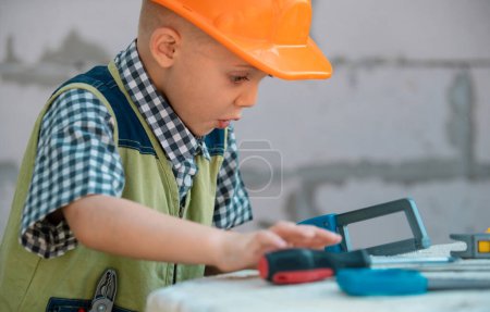 Photo for Preschool boy trying to saw, Child sawing on a construction site near house wall. Kids builder and repair - Royalty Free Image