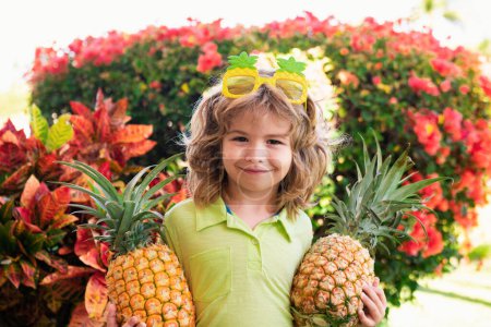 Photo for Young boy holding pineapple and smiling outdoor - Royalty Free Image