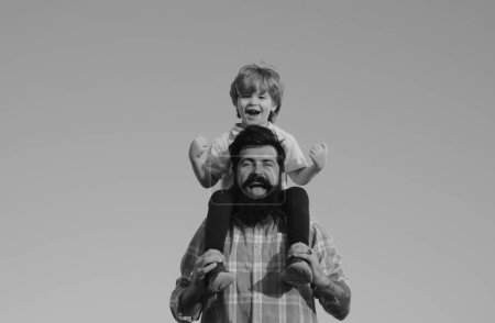 Téléchargez les photos : Portrait de père heureux donnant fils balade sur ses épaules. Mignon garçon avec papa jouant en plein air. Un fils qui serre son père contre le ciel. Famille des générations - en image libre de droit
