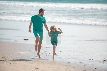 Foto de Concepto familiar feliz. Padre e hijo corriendo en la playa de verano. Papá y el niño jugando al aire libre - Imagen libre de derechos