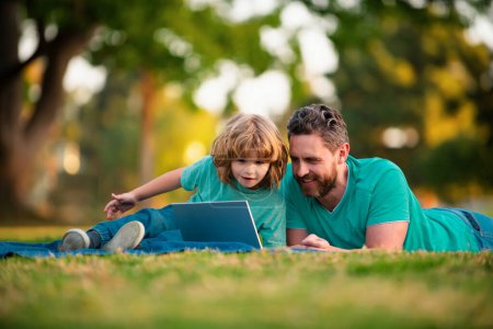 Foto de Padre e hijo con un portátil en la naturaleza en el parque - Imagen libre de derechos