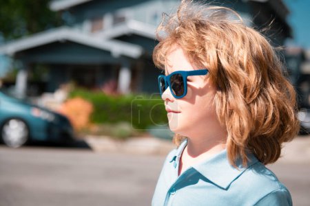 Foto de Retrato de niño pequeño. Concepto de cara a los niños en gafas de sol de cerca. Cabeza disparar niño casa al aire libre, cerca de retrato de la casa - Imagen libre de derechos