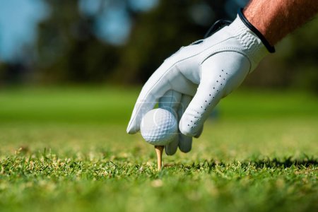 Golfer hitting golf shot with club on course. Hand with golf glove