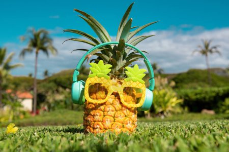 Téléchargez les photos : Ananas avec ananas drôles lunettes de soleil et écouteurs écoute de la musique sur fond d'été - en image libre de droit