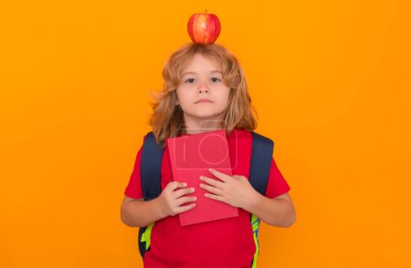 Photo for Apple on head, idea concept. Child from elementary school with book and apple isolated on yellow background. Little student, clever nerd pupil ready to study - Royalty Free Image