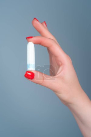 Photo for Hand holding menstruation tampon. Womens menstrual cramps. Menstruation. Feminine tampon. Hygienic tampon in female hand close-up. Critical days. Womens and gynecological health care. Cotton tampon - Royalty Free Image